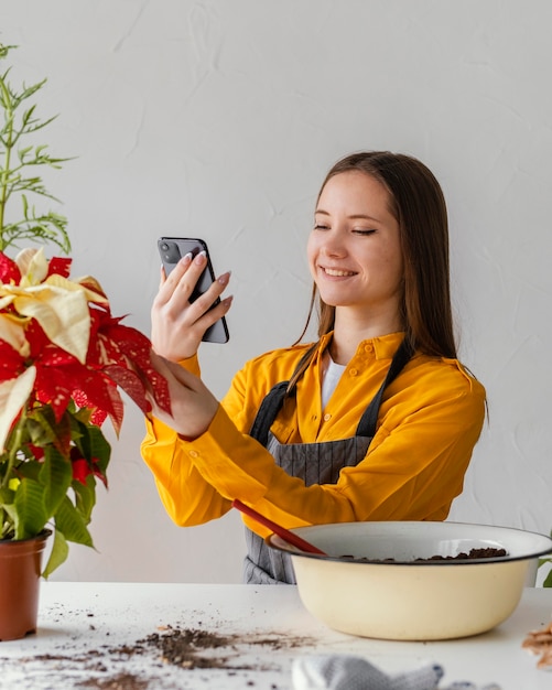 Foto gratuita mujer joven tomando una foto de su planta