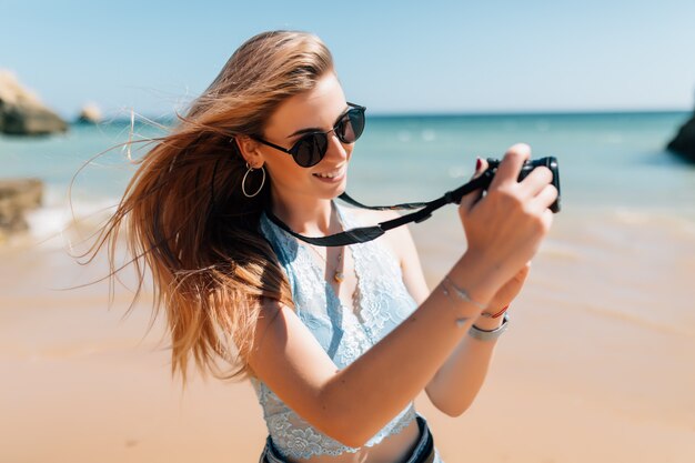 Mujer joven tomando fotos con cámara de fotos en la playa