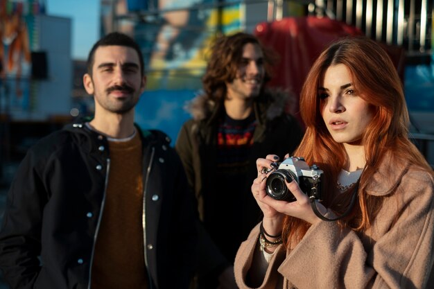 Mujer joven tomando fotos cerca de sus amigos