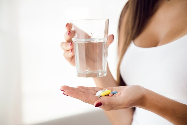 Mujer joven tomando pastillas en casa.