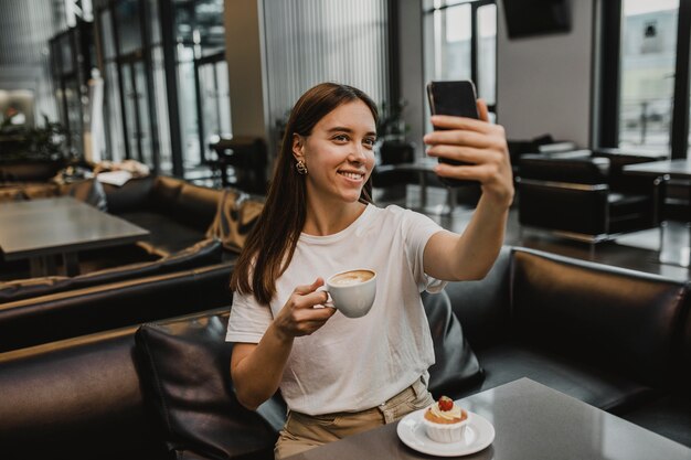 Mujer joven tomando un selfie en la cafetería.