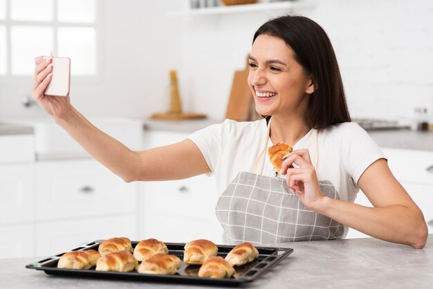 Mujer joven tomando un selfie en la cocina