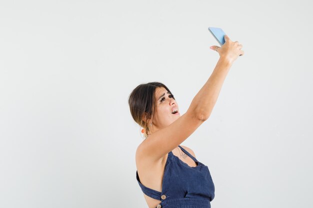 Mujer joven tomando selfie en teléfono móvil en vestido