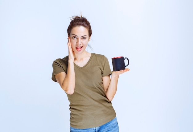 Mujer joven tomando una taza de bebida y disfrutando del sabor