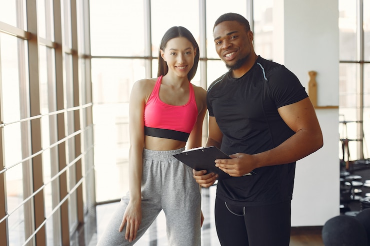 Foto gratuito mujer joven en un top rosa de pie con un entrenador