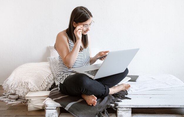 Una mujer joven trabaja de forma remota en una computadora en casa. Freelancer y trabajo en Internet.