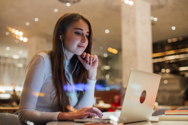 Mujer joven trabaja en un portátil en auriculares en la oficina
