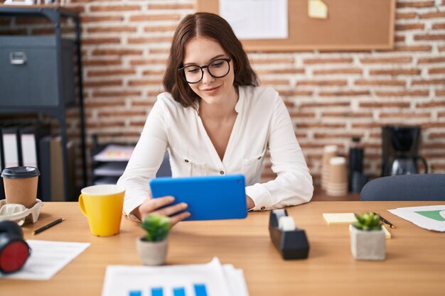 Mujer joven trabajadora de negocios usando touchpad trabajando en la oficina