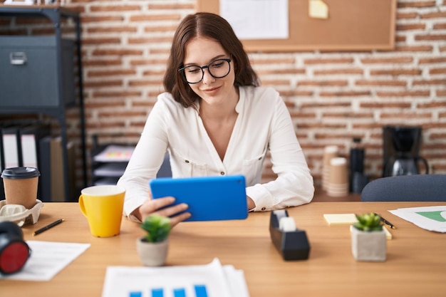 Mujer joven trabajadora de negocios usando touchpad trabajando en la oficina