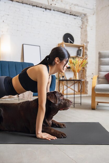 Mujer joven trabajando en casa. Ejercicios de yoga con el perro