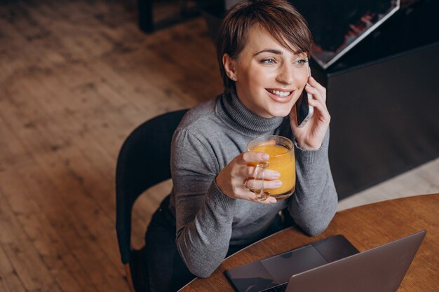 Mujer joven trabajando en la computadora y bebiendo té caliente