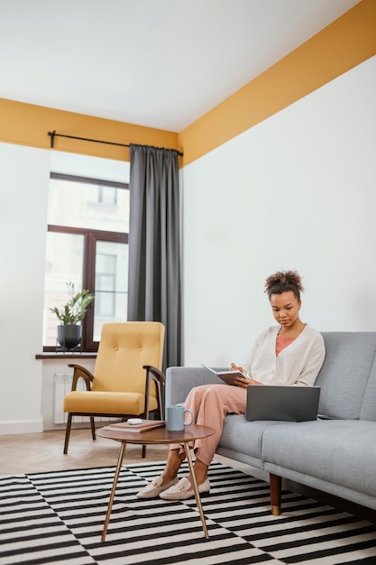 Foto gratuita mujer joven trabajando mientras está sentado en el sofá