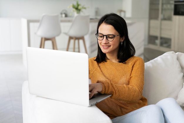 Mujer joven trabajando en su computadora portátil en casa