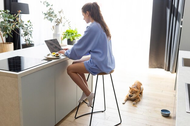 Mujer joven trabajando en su computadora portátil junto a su perro