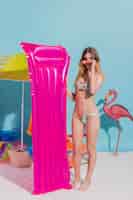 Foto gratuita mujer joven en traje de baño y gafas de sol con lilo rosa