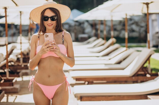 Mujer joven en traje de baño junto a la piscina