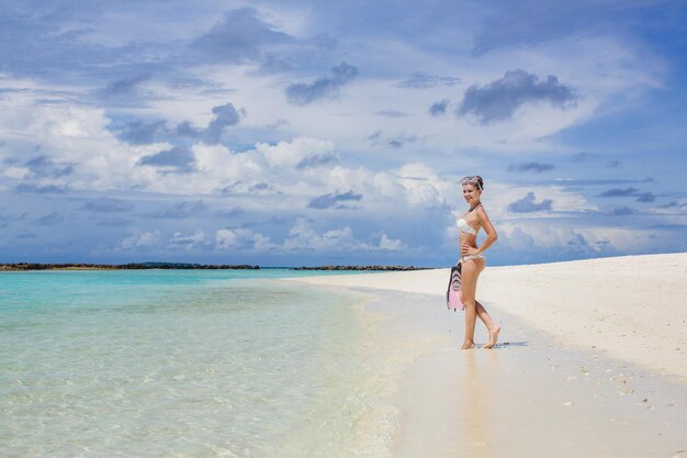mujer joven en traje de baño en la playa en Maldivas