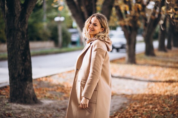 Mujer joven en traje beige afuera en un parque de otoño