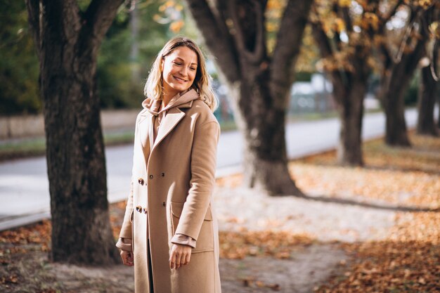 Mujer joven en traje beige afuera en un parque de otoño