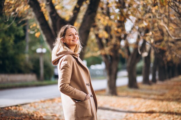 Mujer joven en traje beige afuera en un parque de otoño