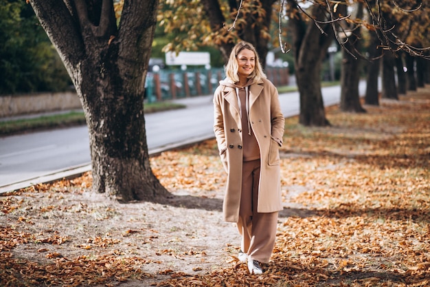 Mujer joven en traje beige afuera en un parque de otoño