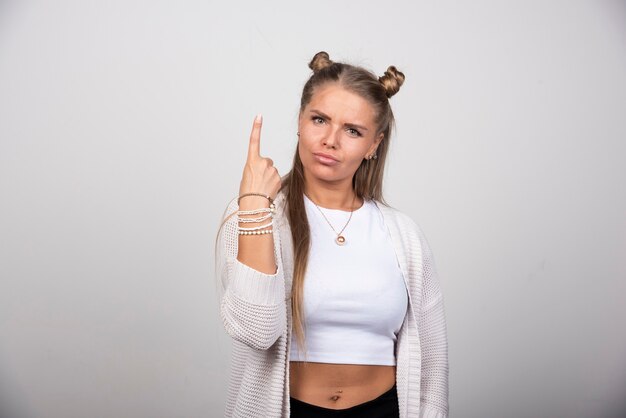 Mujer joven en traje blanco apuntando al revés.