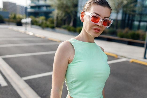 mujer joven en traje casual usando auriculares inalámbricos al aire libre