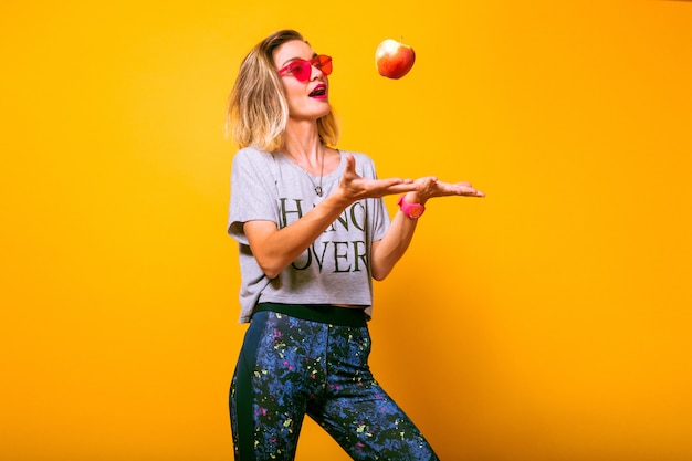 Mujer joven en traje deportivo brillante jugando con apple