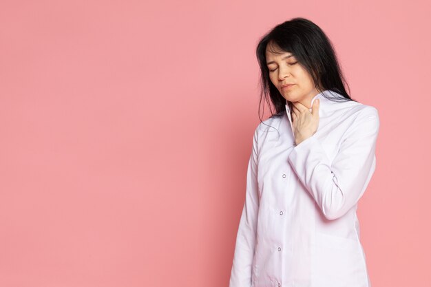Mujer joven en traje médico blanco que tiene problemas con su aliento en rosa