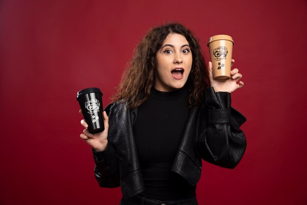 Mujer joven en traje negro con dos tazas.