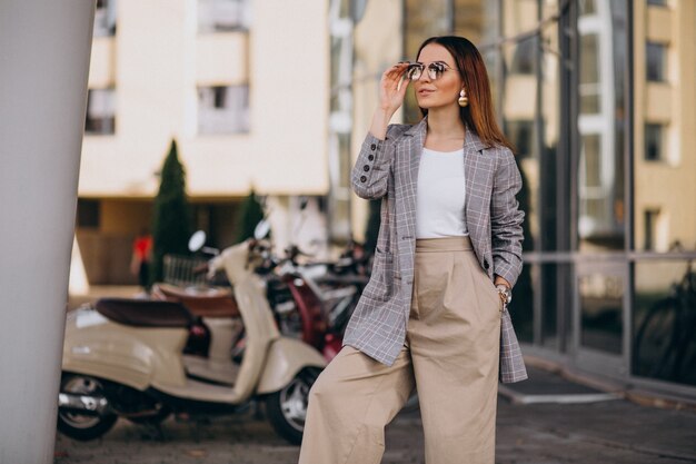 Mujer joven en traje de pie junto a la moto