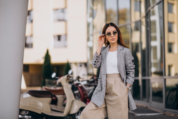 Mujer joven en traje de pie junto a la moto