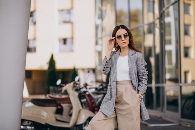 Mujer joven en traje de pie junto a la moto