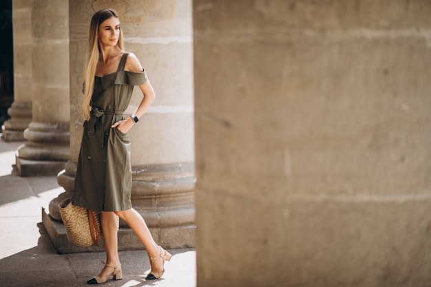 Mujer joven en traje de verano por un edificio antiguo