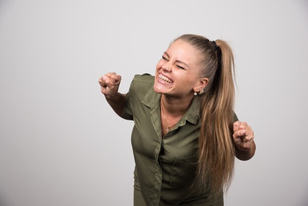 Mujer joven en traje verde sintiéndose feliz.