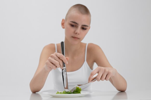 Mujer joven con un trastorno alimentario con ganas de comer lechuga