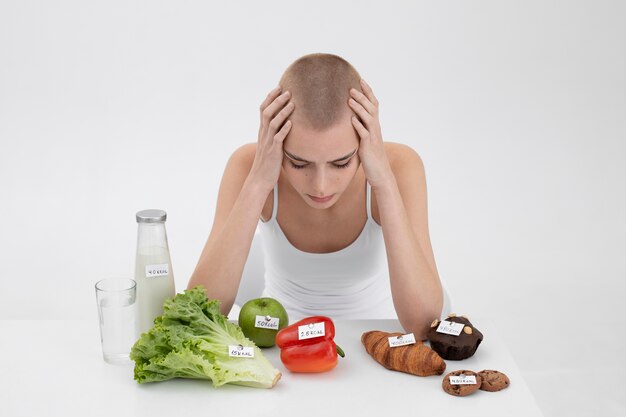 Mujer joven con un trastorno alimentario junto a alimentos con números de calorías