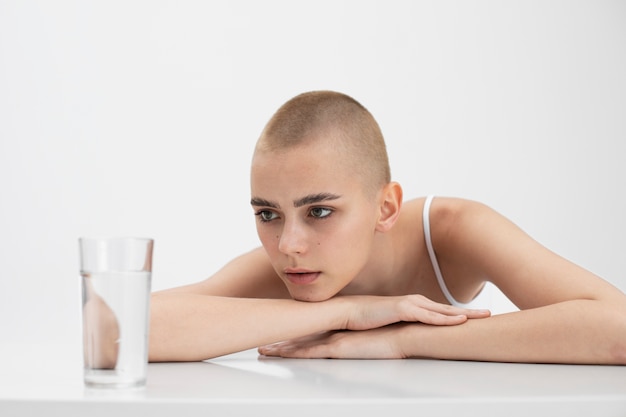 Mujer joven con un trastorno alimentario mirando un vaso de agua