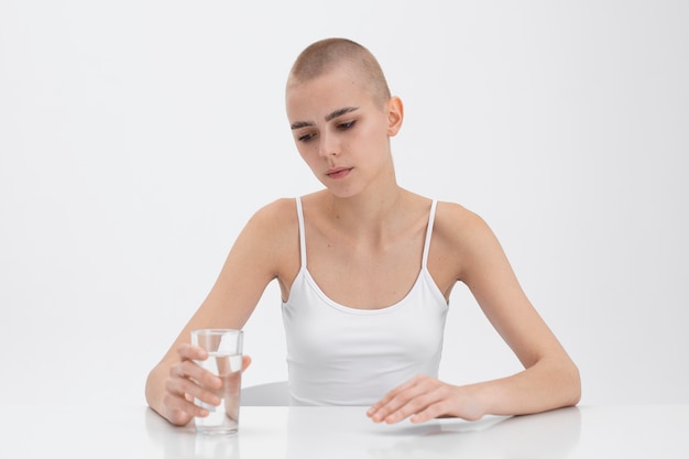 Mujer joven con un trastorno alimentario mirando un vaso de agua