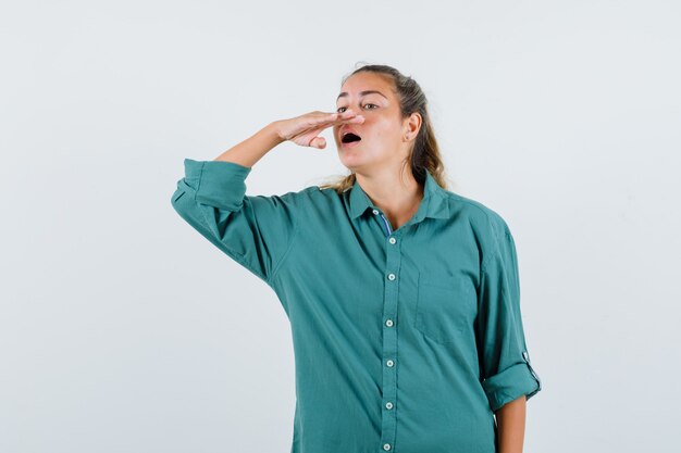 Mujer joven tratando de estornudar en blusa verde y mirando feliz