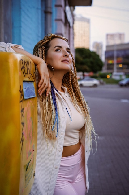 mujer joven con trenzas afro zizi y maquillaje brillante en una gran ciudad, retrato. Peinados con trenzas zizi.