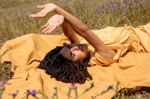 Mujer joven tumbada en tela amarilla en la naturaleza