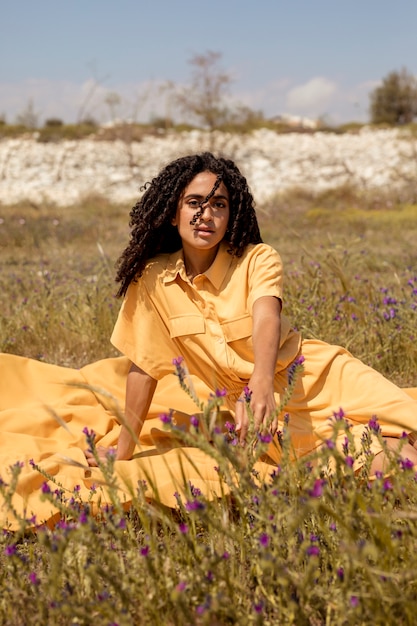 Mujer joven tumbada en tela amarilla en la naturaleza