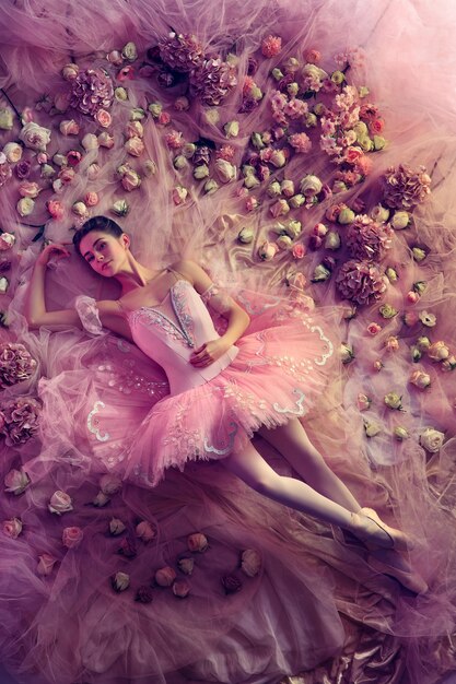 Mujer joven en tutú de ballet rosa rodeado de flores