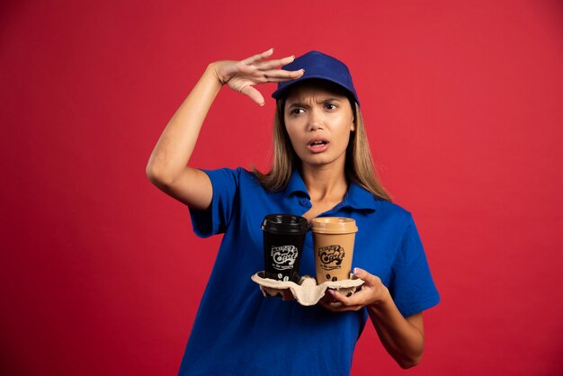 Foto gratuita mujer joven en uniforme azul sosteniendo una caja de dos tazas.