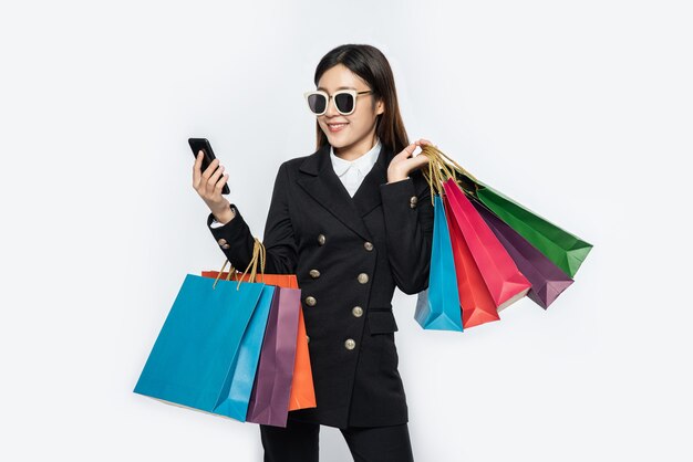 Mujer joven usa gafas y compra en teléfonos inteligentes.