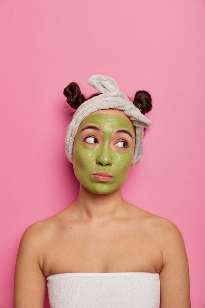 Mujer joven usa tratamientos de piel de mascarilla facial natural después de tomar un baño