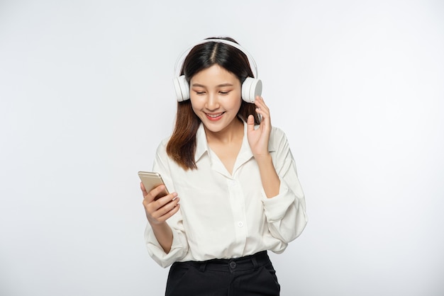 Mujer joven usando audífonos y escuchando música en un teléfono inteligente