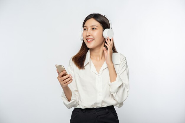 Mujer joven usando audífonos y escuchando música en un teléfono inteligente