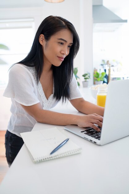 Mujer joven usando laptop y notebook con bolígrafo para notas